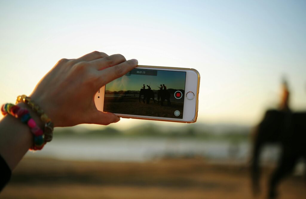 Hand holds cell phone camera capturing a video.