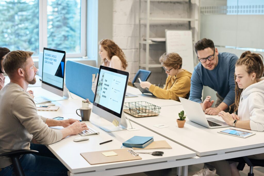 Instructor in a computer lab with his students, working on various devices.